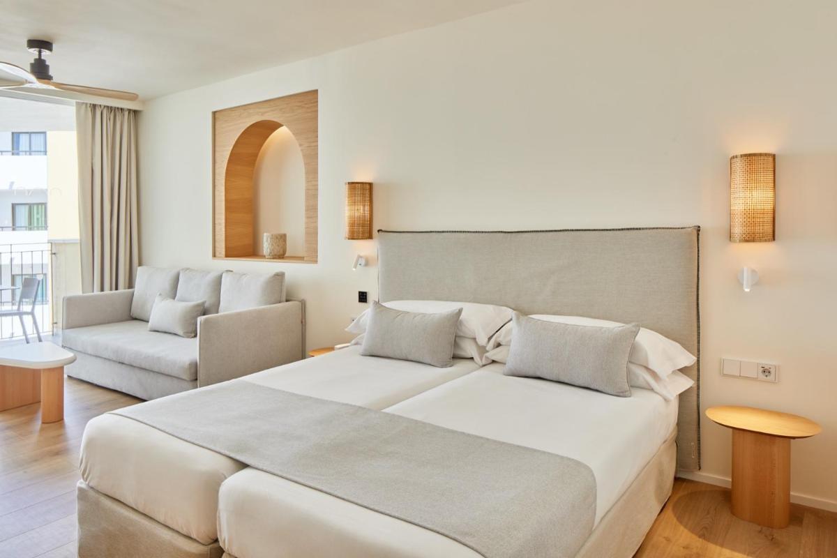 Un dormitorio con una gran cama blanca y un sofá. en Hotel & Spa Blau Parc, en San Antonio