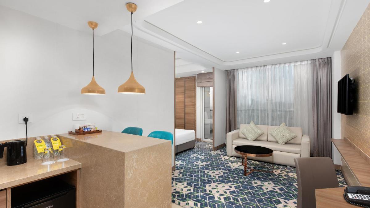 a living room with a kitchen and a living room with a couch at Holiday Inn Gurugram Sector 90 by IHG in Gurgaon