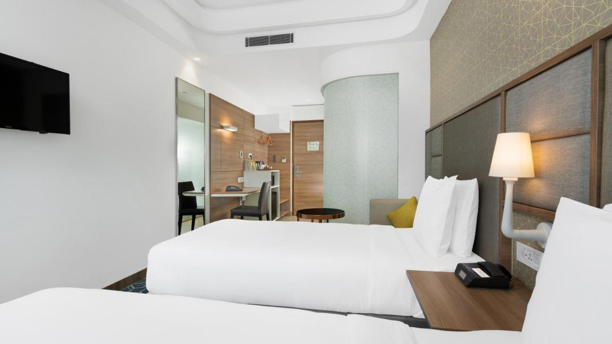 a hotel room with two beds and a desk at Holiday Inn Gurugram Sector 90 by IHG in Gurgaon