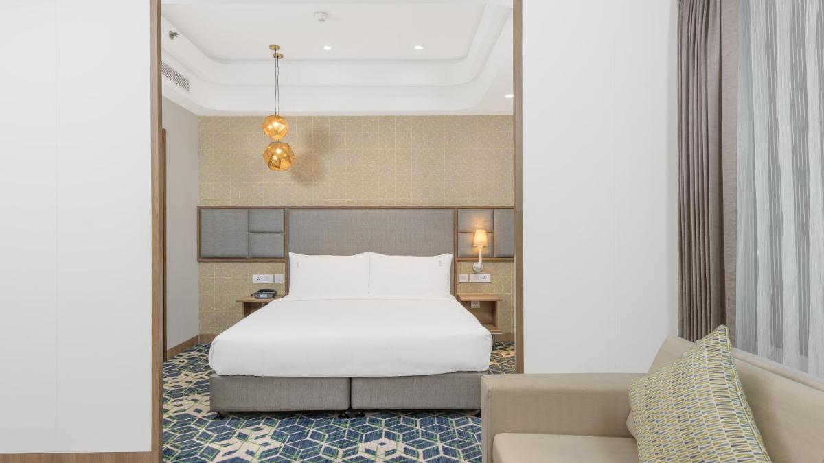 a bedroom with a white bed and a couch at Holiday Inn Gurugram Sector 90 by IHG in Gurgaon
