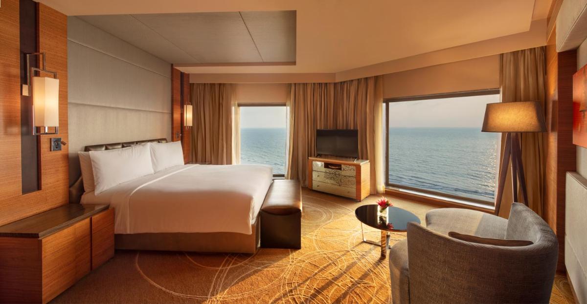 a bedroom with a bed and a view of the ocean at JW Marriott Mumbai Juhu in Mumbai a bedroom with a bed and a view of the ocean at JW Marriott Mumbai Juhu in Mumbai