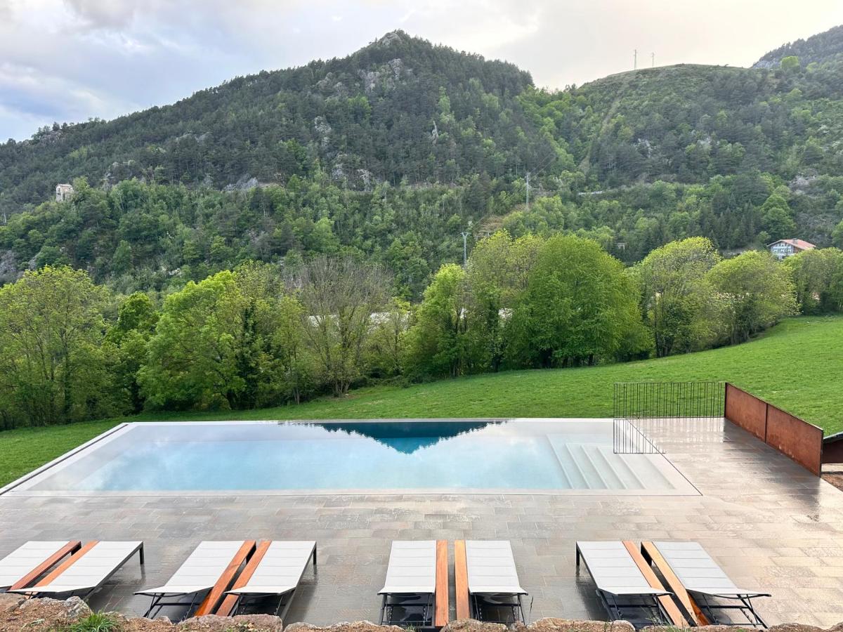 Una piscina con sillas y montañas al fondo. en Hotel Rural-Spa Resguard Dels Vents, en Ribes de Freser