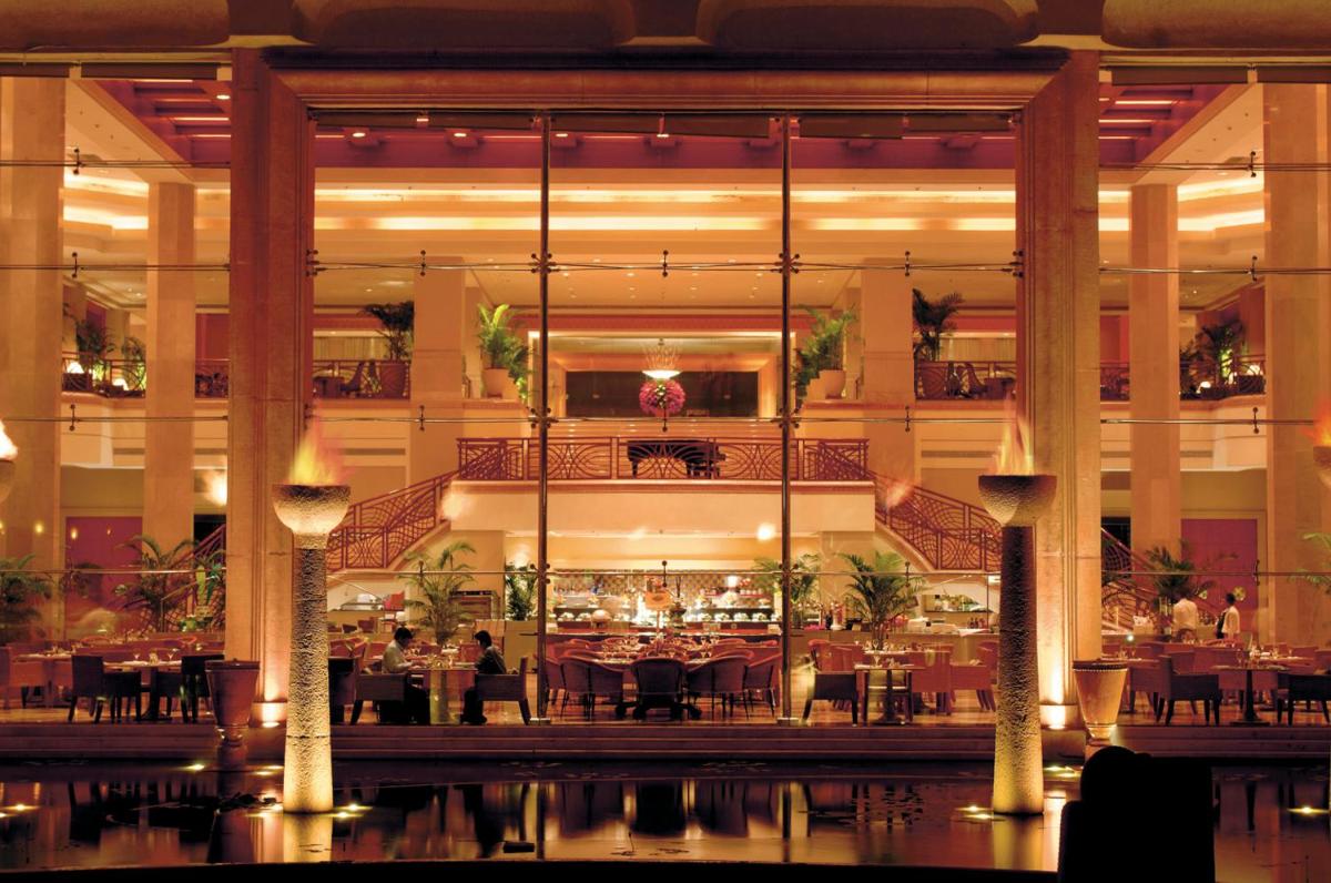a restaurant with tables and chairs in a large building at JW Marriott Mumbai Juhu in Mumbai