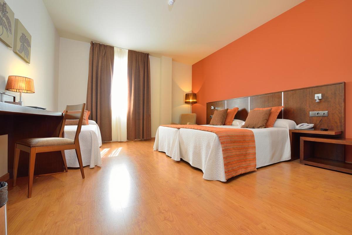 Una habitación de hotel con dos camas y un escritorio. en Hotel Spa Norat Torre Do Deza 4* Superior, en Lalín