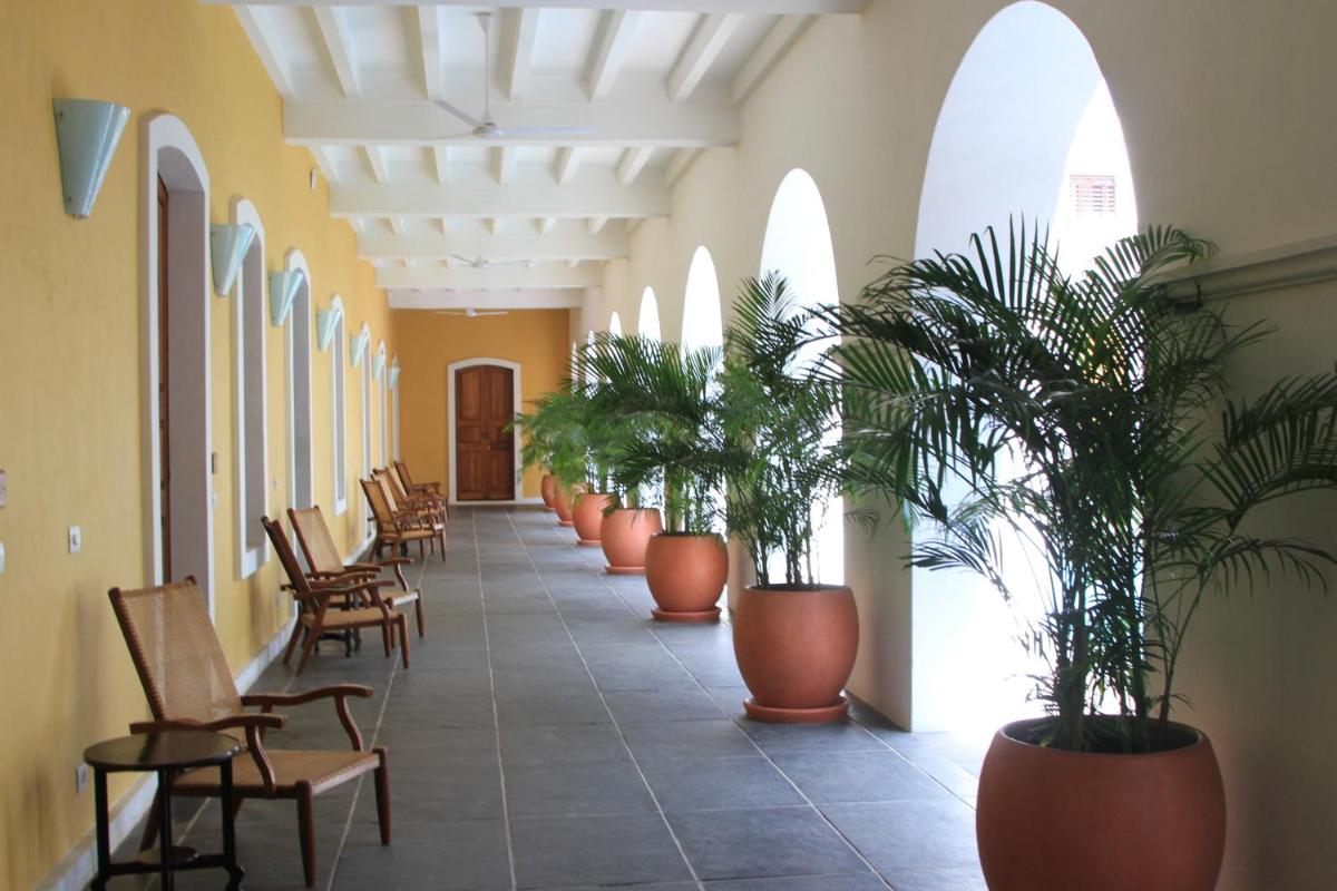 a hallway with chairs and potted plants at Palais De Mahe - A CGH Earth Experience in Puducherry