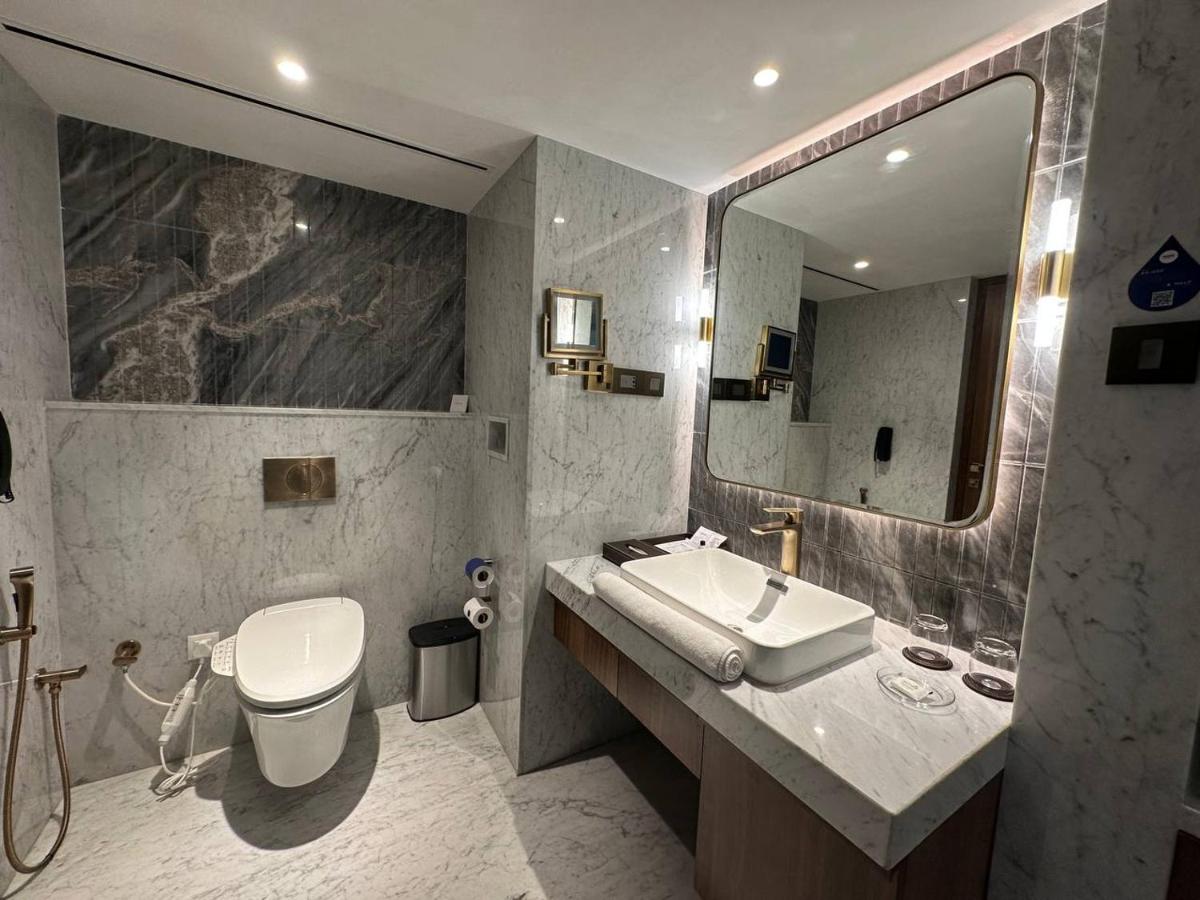 a bathroom with a sink and a toilet and a mirror at Radisson Blu Hotel & Suites GRT Chennai in Chennai