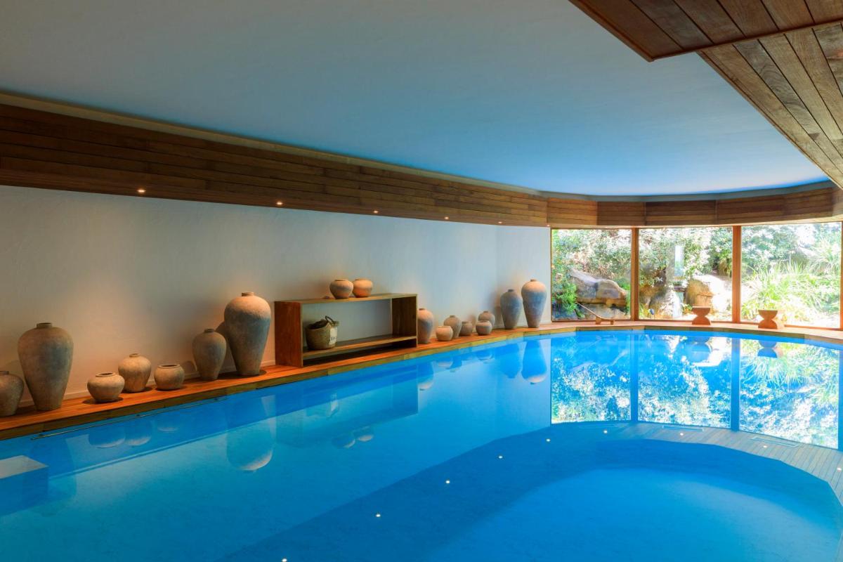 une grande piscine dans une pièce avec des vases dans l'établissement Grand Hôtel De Cala Rossa & Spa Nucca, à Porto-Vecchio