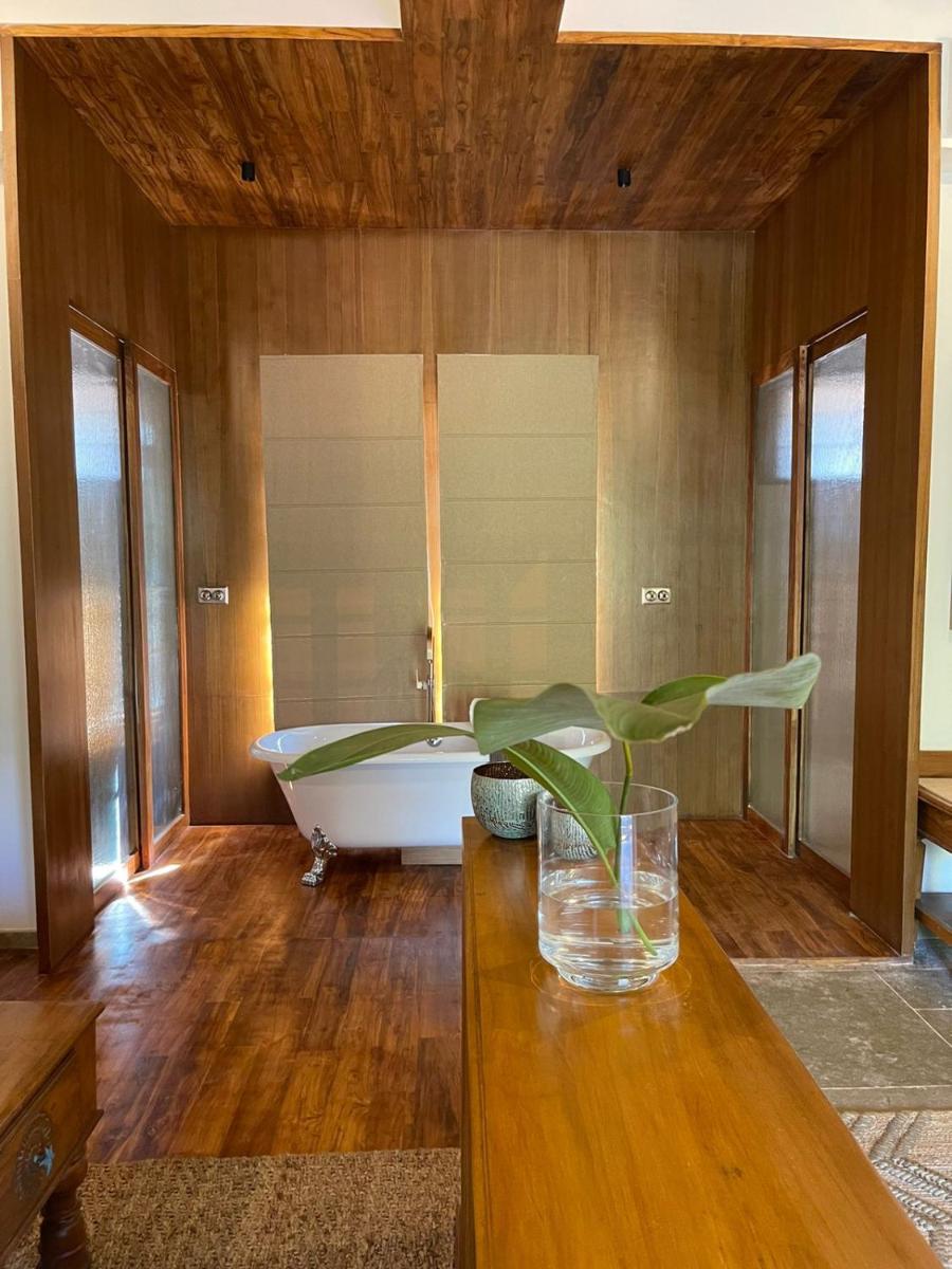 a bathroom with a tub and a table with a vase on it at The Postcard Saligao in Calangute