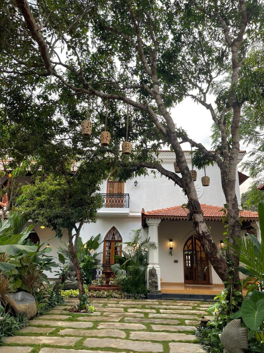 a white house with trees in front of it at The Postcard Saligao in Calangute