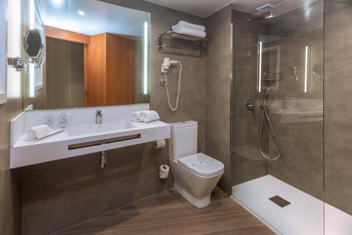 Un baño con lavabo, inodoro y ducha. en GHT Aquarium & Spa, en Lloret de Mar