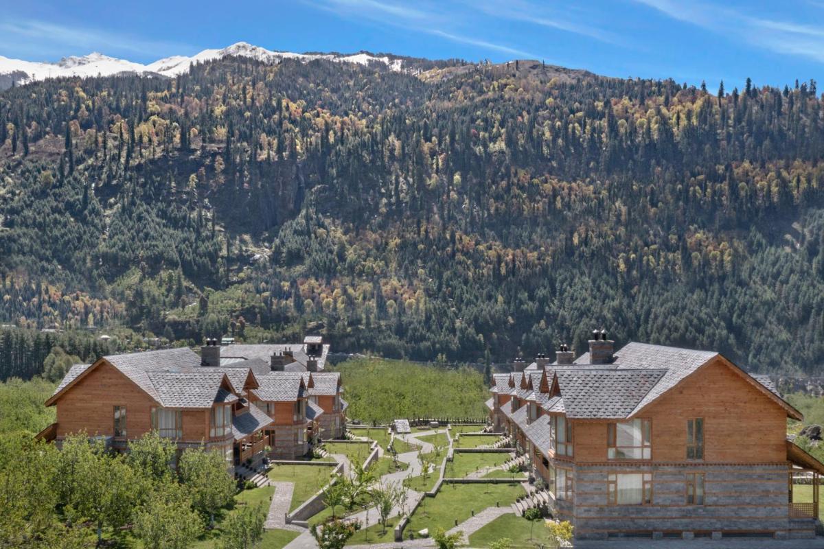 a row of houses in front of a mountain at Welcomhotel By ITC Hotels, Hamsa Manali in Manāli a row of houses in front of a mountain at Welcomhotel By ITC Hotels, Hamsa Manali in Manāli