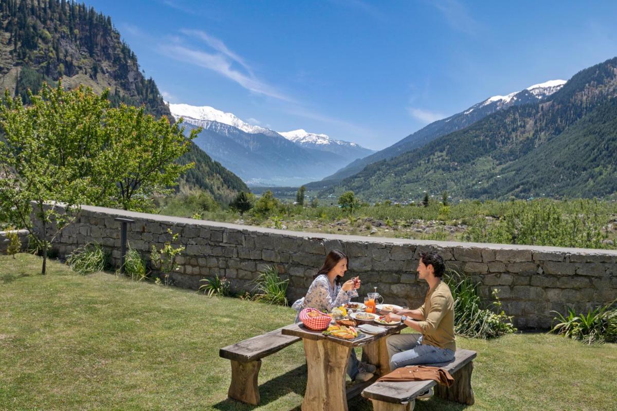a man and woman sitting at a table with food at Welcomhotel By ITC Hotels, Hamsa Manali in Manāli a man and woman sitting at a table with food at Welcomhotel By ITC Hotels, Hamsa Manali in Manāli