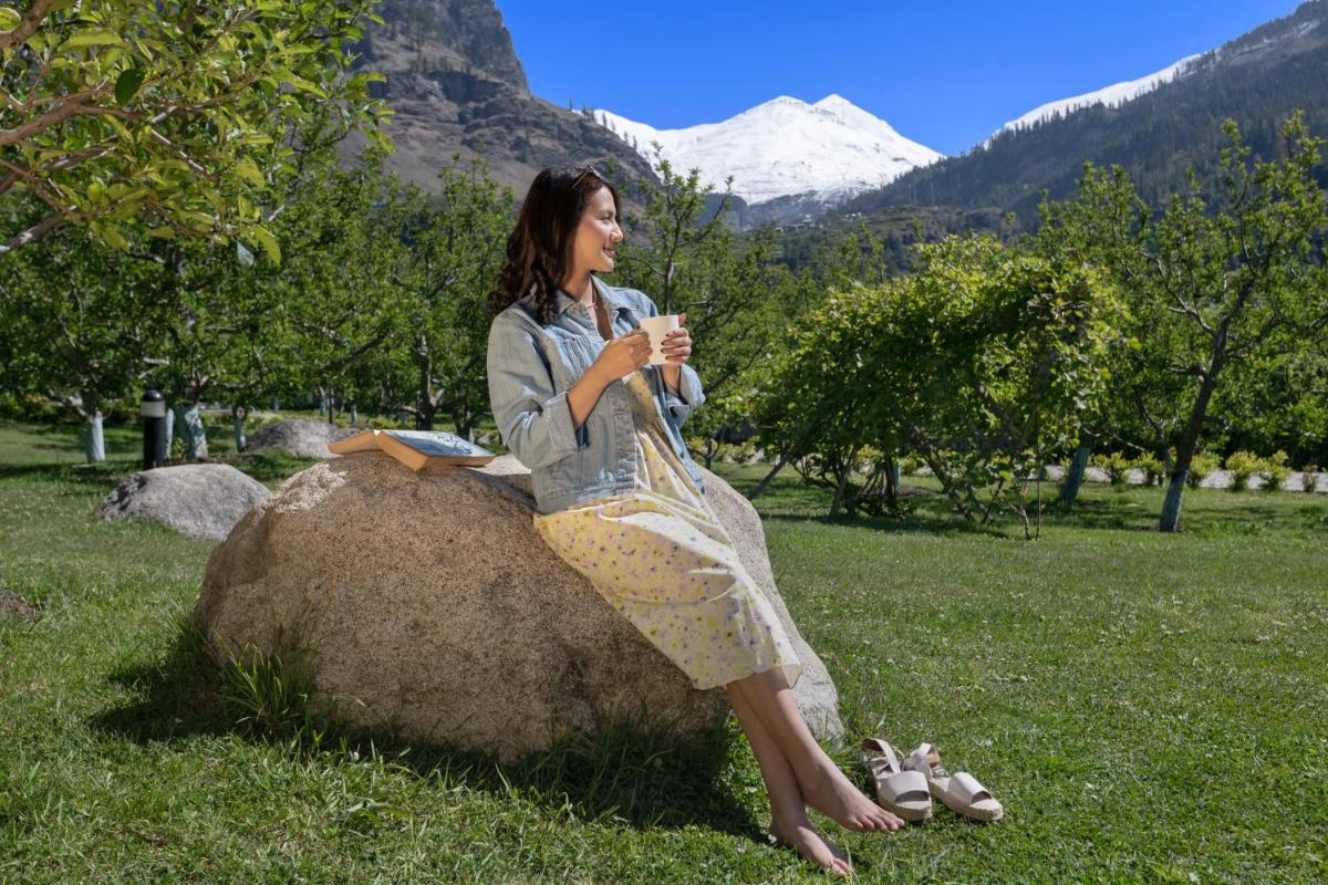 a woman sitting on a rock in a field at Welcomhotel By ITC Hotels, Hamsa Manali in Manāli a woman sitting on a rock in a field at Welcomhotel By ITC Hotels, Hamsa Manali in Manāli
