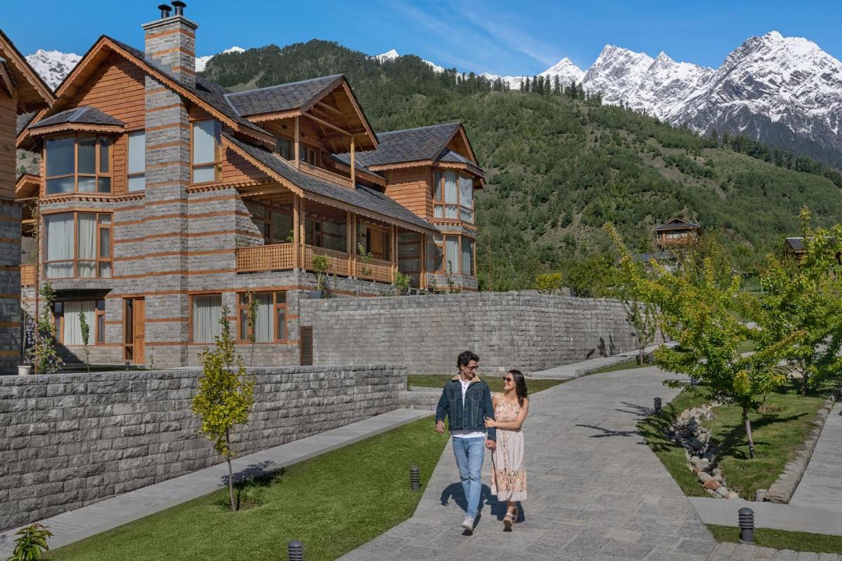a man and a woman walking in front of a house at Welcomhotel By ITC Hotels, Hamsa Manali in Manāli a man and a woman walking in front of a house at Welcomhotel By ITC Hotels, Hamsa Manali in Manāli