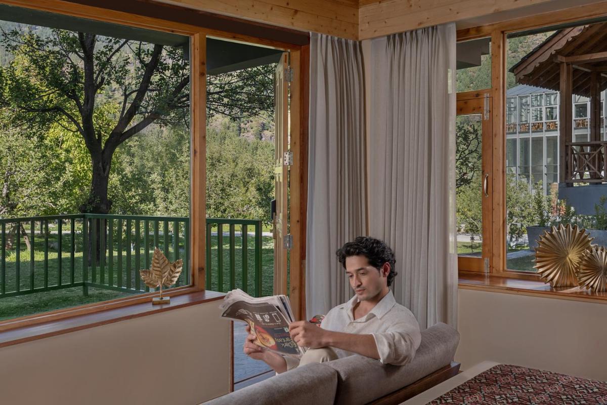 a man sitting on a couch reading a magazine at Welcomhotel By ITC Hotels, Hamsa Manali in Manāli a man sitting on a couch reading a magazine at Welcomhotel By ITC Hotels, Hamsa Manali in Manāli