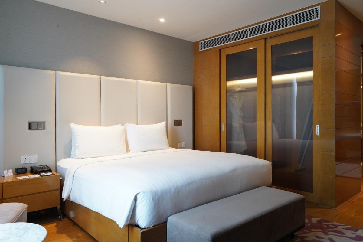 a bedroom with a large white bed and a bench at Marriott Executive Apartments Hyderabad in Hyderabad