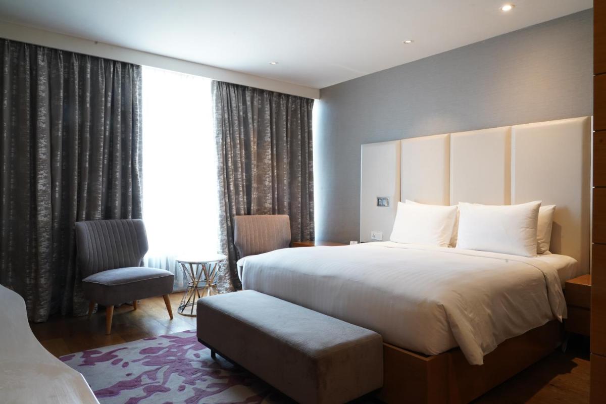 a hotel room with a large bed and a chair at Marriott Executive Apartments Hyderabad in Hyderabad