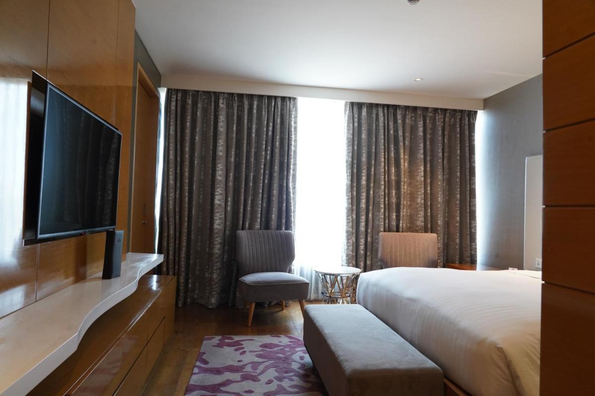 a hotel room with a bed and a flat screen tv at Marriott Executive Apartments Hyderabad in Hyderabad
