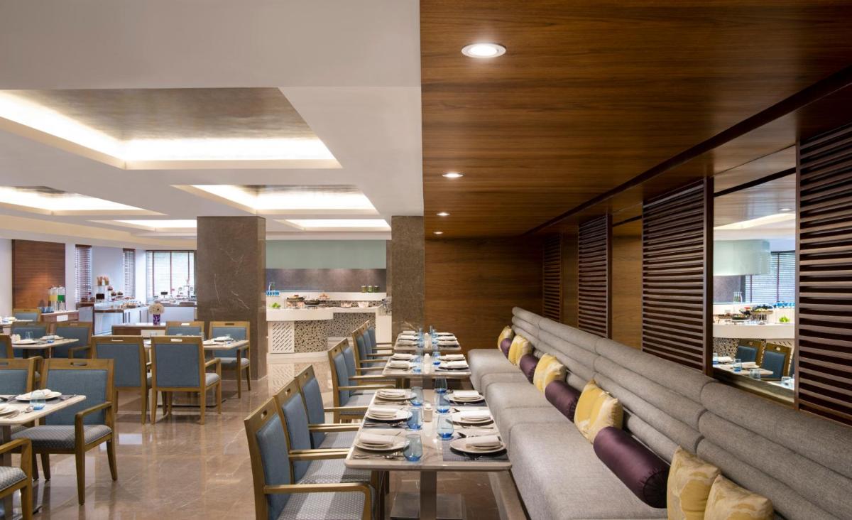 a dining room with long tables and chairs at Vivanta Thiruvananthapuram in Trivandrum
