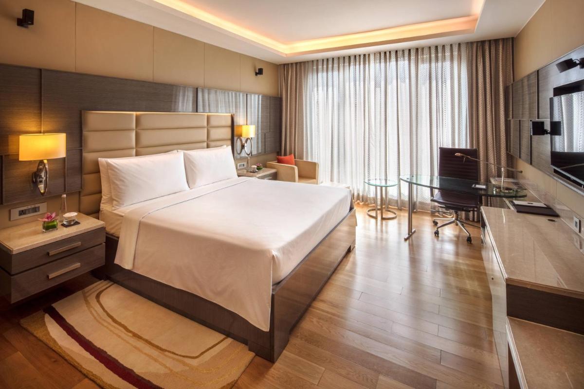 a bedroom with a bed and a desk and a television at JW Marriott Mumbai Sahar Airport in Mumbai a bedroom with a bed and a desk and a television at JW Marriott Mumbai Sahar Airport in Mumbai