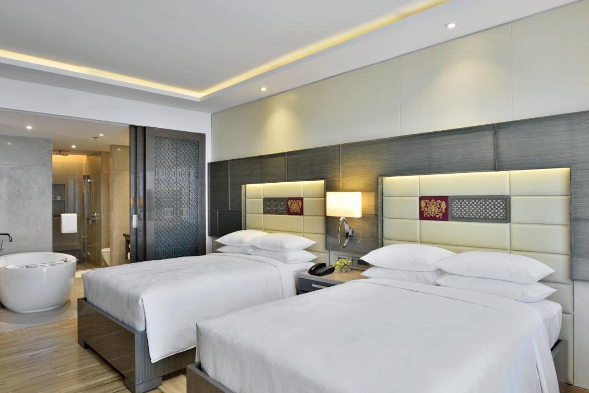 a hotel room with two beds and a bath tub at JW Marriott Mumbai Sahar Airport in Mumbai a hotel room with two beds and a bath tub at JW Marriott Mumbai Sahar Airport in Mumbai