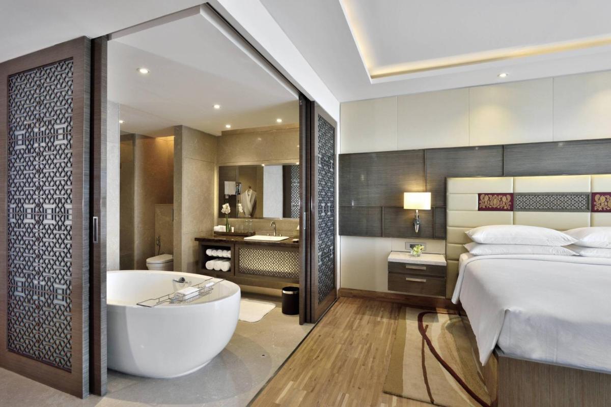 a bedroom with a tub and a bed and a bathroom at JW Marriott Mumbai Sahar Airport in Mumbai a bedroom with a tub and a bed and a bathroom at JW Marriott Mumbai Sahar Airport in Mumbai
