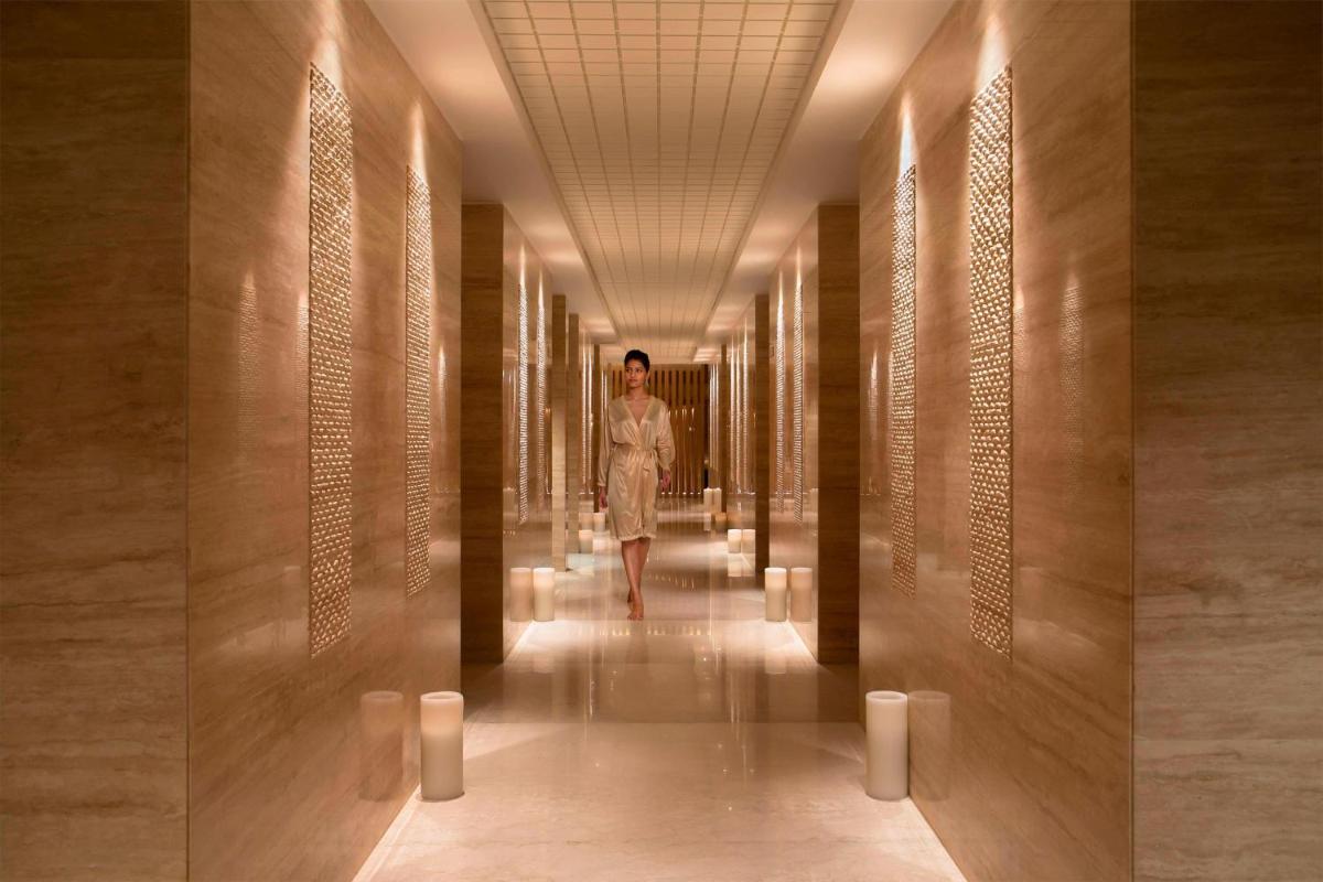 a woman walking down a hallway in a building at JW Marriott Mumbai Sahar Airport in Mumbai a woman walking down a hallway in a building at JW Marriott Mumbai Sahar Airport in Mumbai