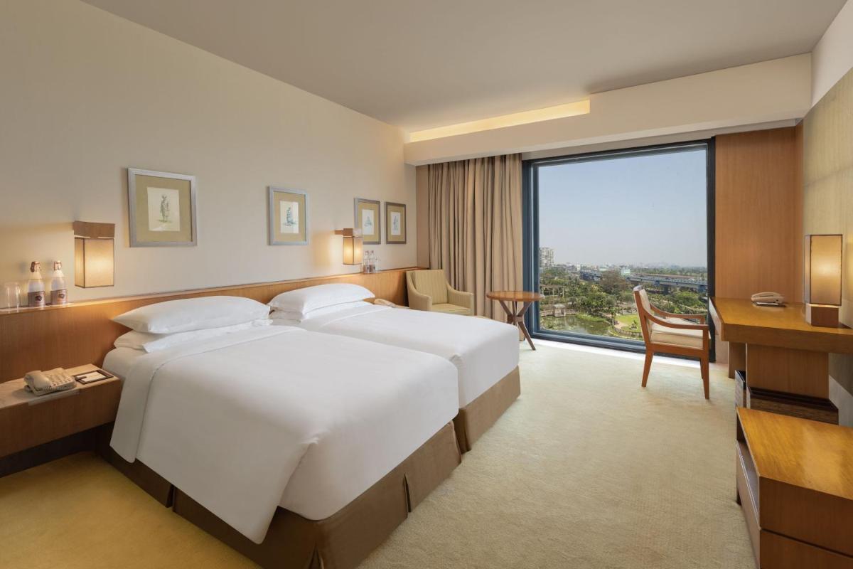 a hotel room with two beds and a desk and a window at ITC Sonar, a Luxury Collection Hotel, Kolkata in Kolkata