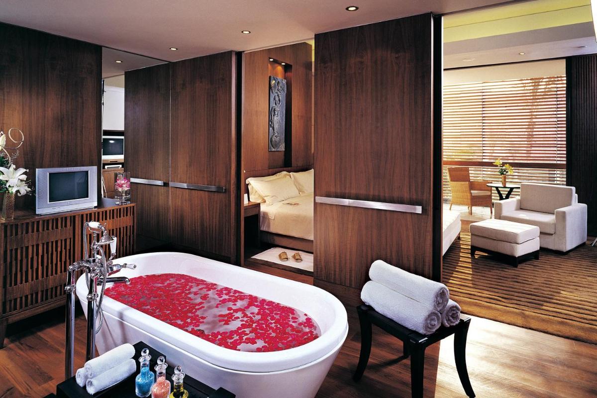 a bathroom with a red bath tub with a bedroom at ITC Sonar, a Luxury Collection Hotel, Kolkata in Kolkata