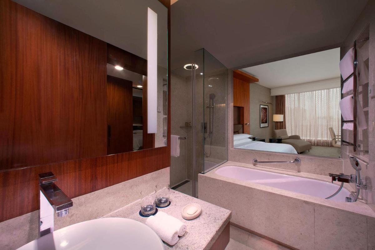 a bathroom with a sink and a tub and a bed at Sheraton Grand Bangalore Hotel at Brigade Gateway in Bengaluru a bathroom with a sink and a tub and a bed at Sheraton Grand Bangalore Hotel at Brigade Gateway in Bengaluru