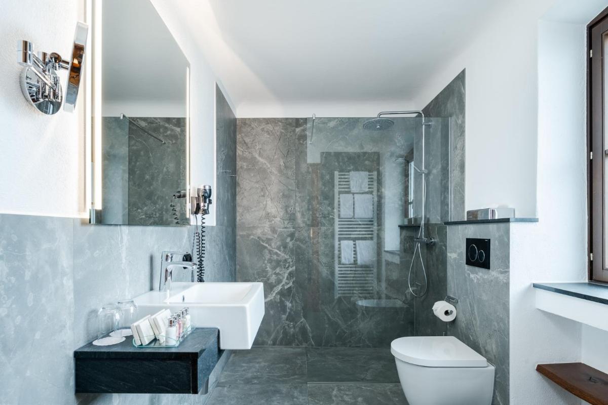 ein Badezimmer mit Waschbecken, Toilette und Dusche in der Unterkunft Hotel Gut Ising in Chieming
