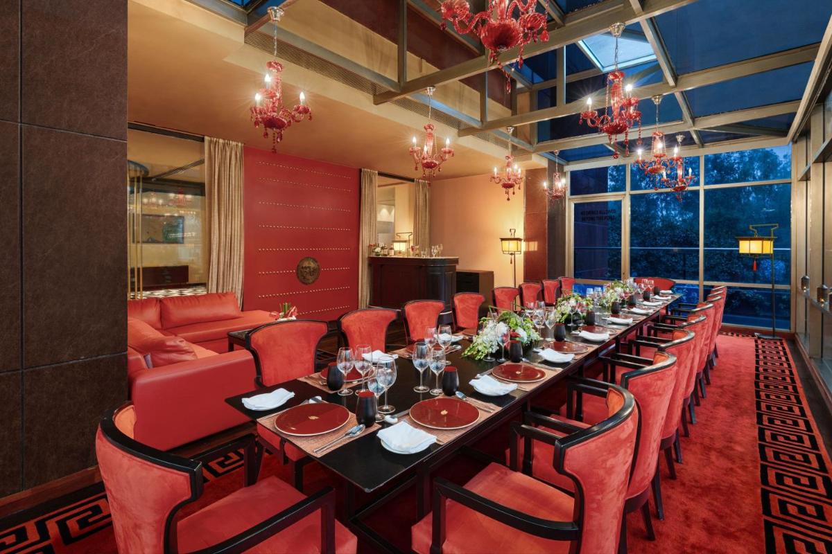 a long dining room with a long table and red chairs at Sheraton New Delhi Hotel in New Delhi a long dining room with a long table and red chairs at Sheraton New Delhi Hotel in New Delhi