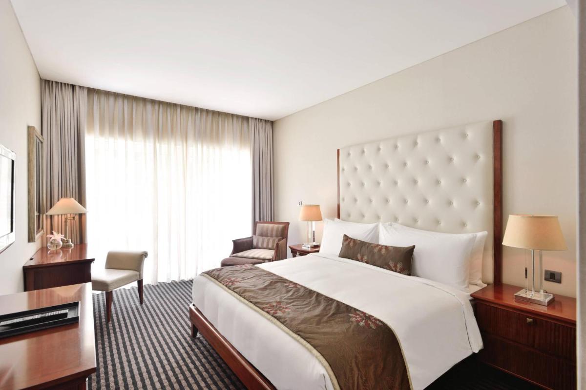 a hotel room with a large bed and a desk at Marriott Suites Pune in Pune