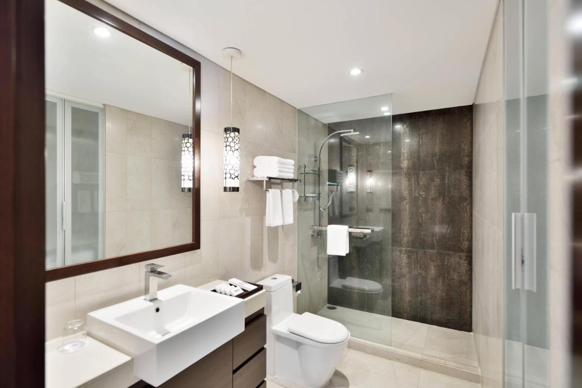 a bathroom with a sink and a toilet and a shower at Marriott Suites Pune in Pune