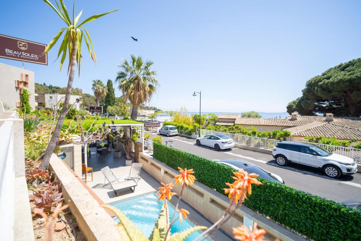 une vue d'une rue avec des voitures garées dans un parking dans l'établissement Hôtel Beau Soleil, au Lavandou