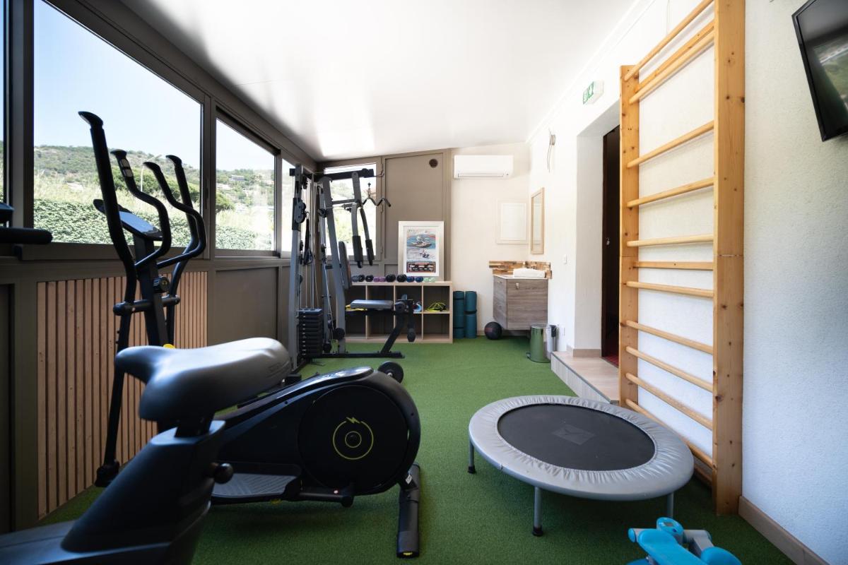 une salle avec une salle de sport avec un tapis roulant et un simulateur dans l'établissement Hôtel Beau Soleil, au Lavandou