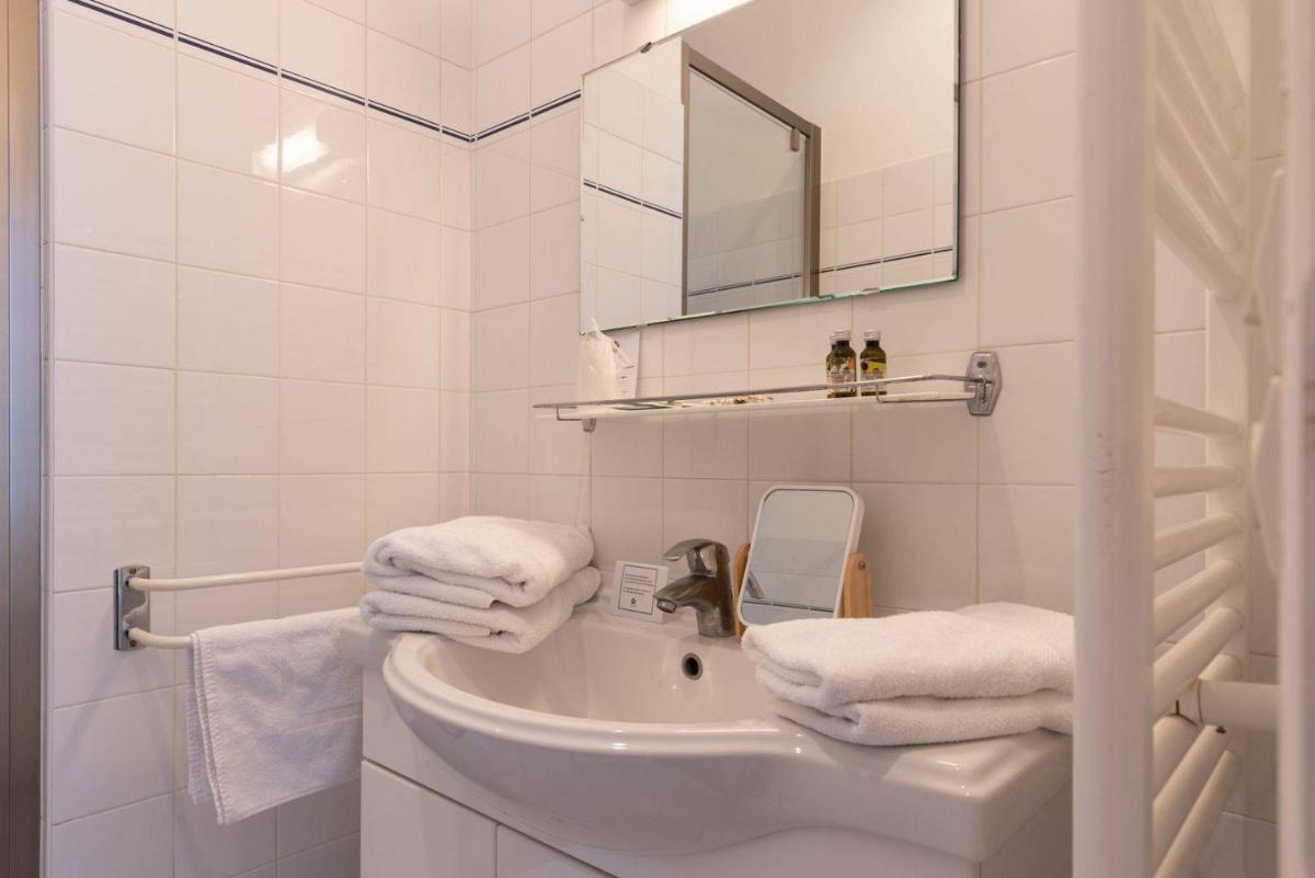 une salle de bain blanche avec un lavabo et un miroir dans l'établissement Le Chat Botté, à Saint-Clément-des-Baleines
