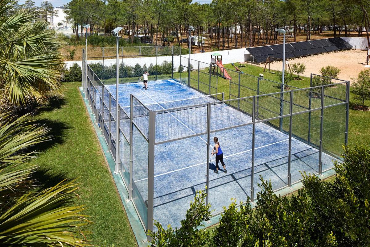 duas pessoas a jogar ténis num campo de ténis em Alcazar Hotel & SPA em Monte Gordo