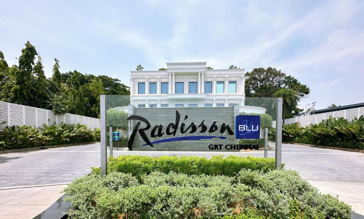 a sign in front of a white building at Radisson Blu Hotel & Suites GRT Chennai in Chennai