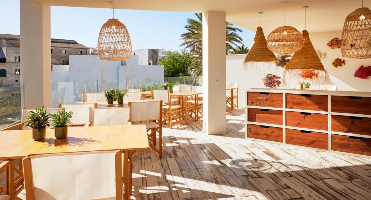 Un comedor con mesas y sillas y un gran ventanal. en Catalonia Mirador des Port, en Mahón