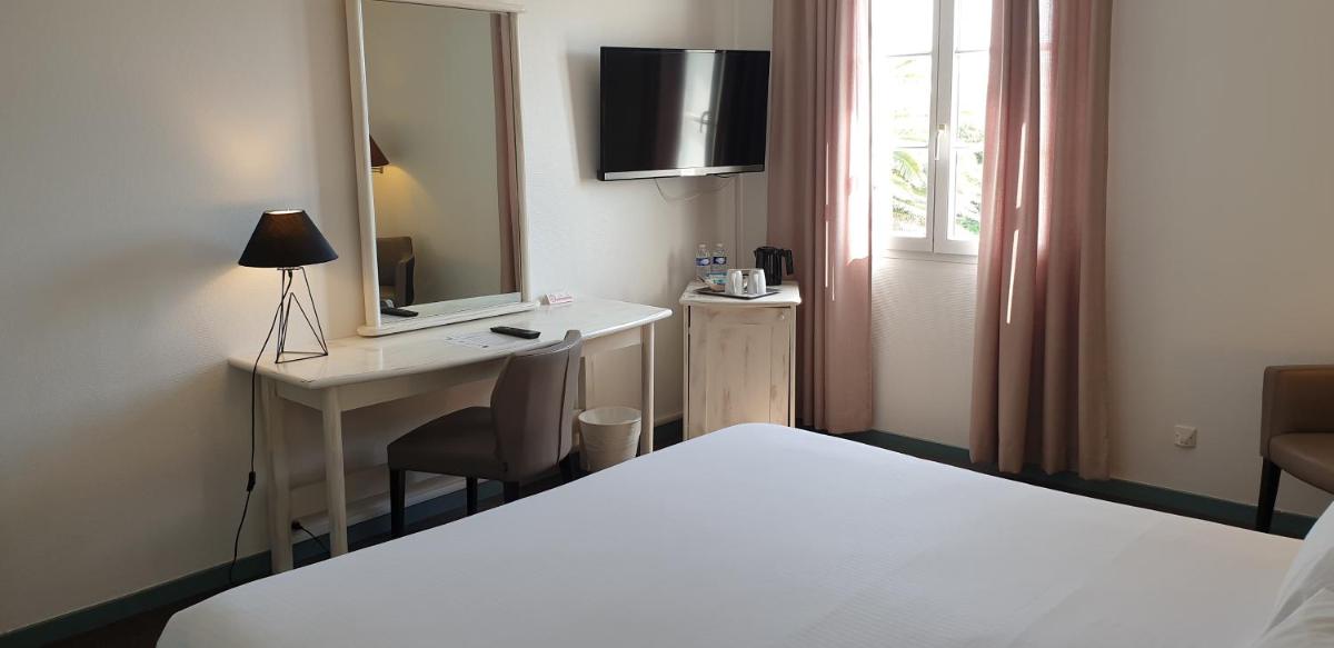 une chambre d'hôtel avec un lit, un bureau et un miroir dans l'établissement Thalacap Île de Ré - Thalasso & Spa, à Ars-en-Ré