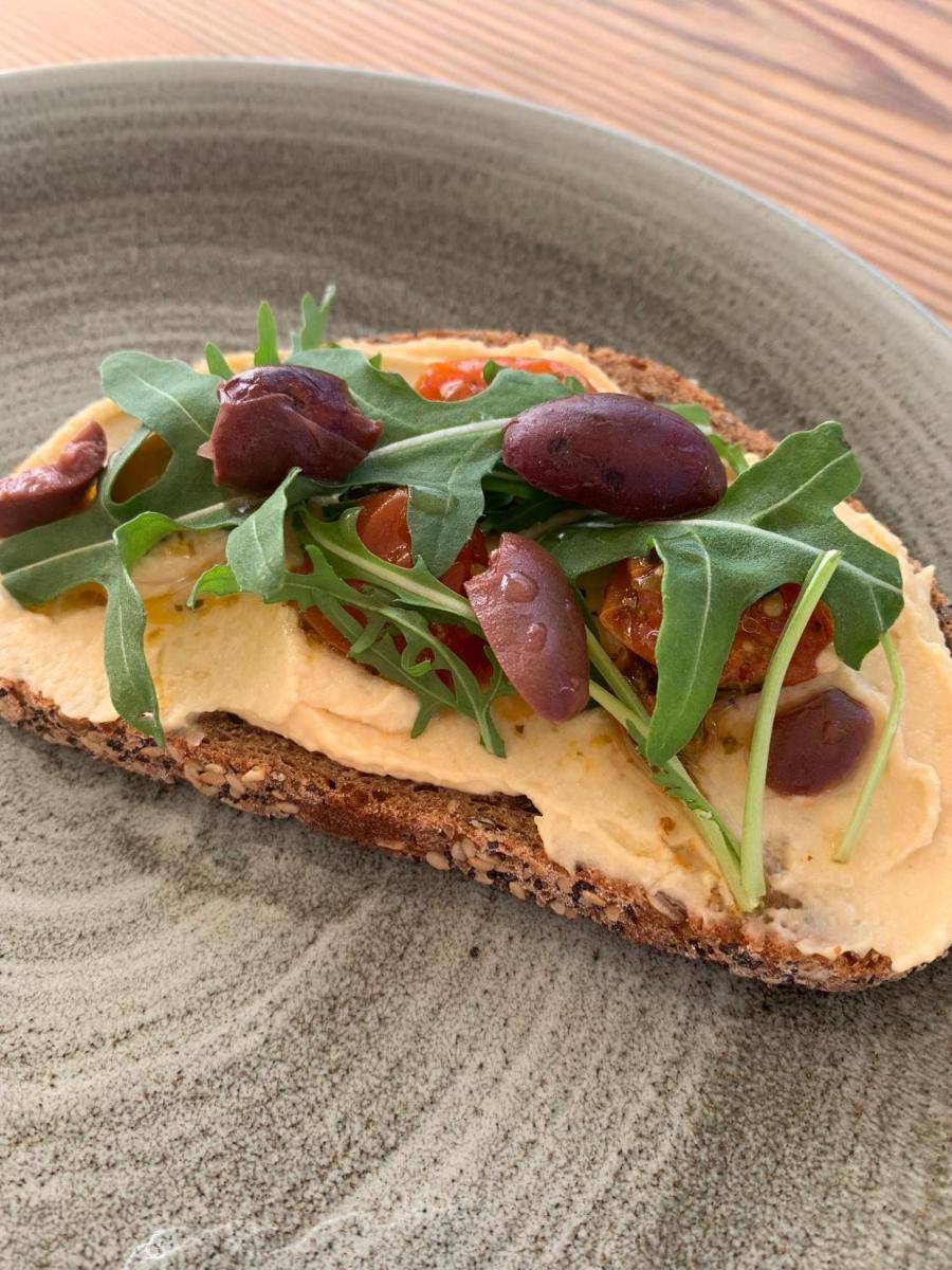 una rebanada de pizza con aceitunas y verduras en un plato en Boutique Hotel Sant Roc & Spa, en Mahón
