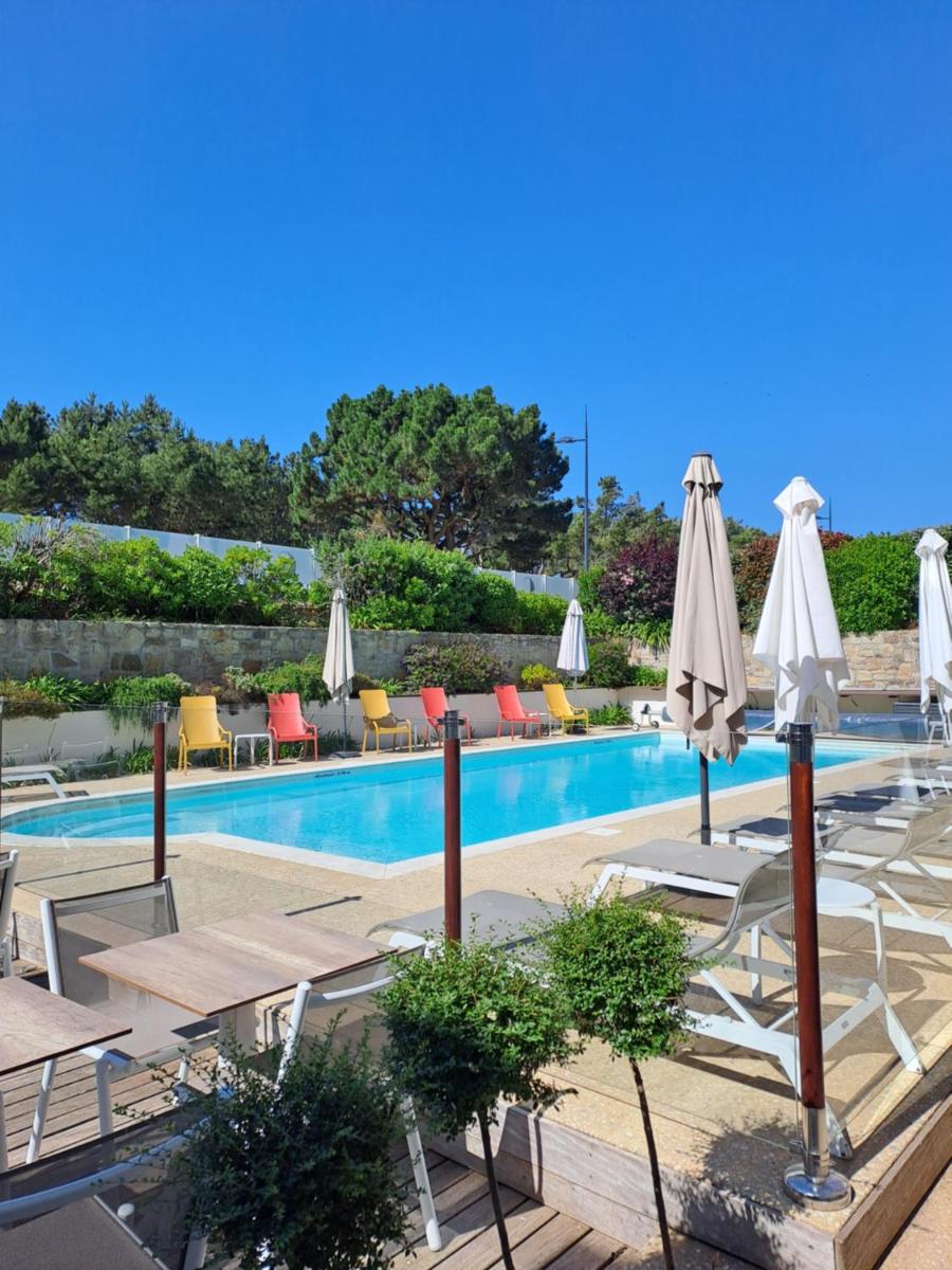 une piscine avec chaises longues et parasols dans l'établissement Le Churchill Hôtel & Spa, à Carnac