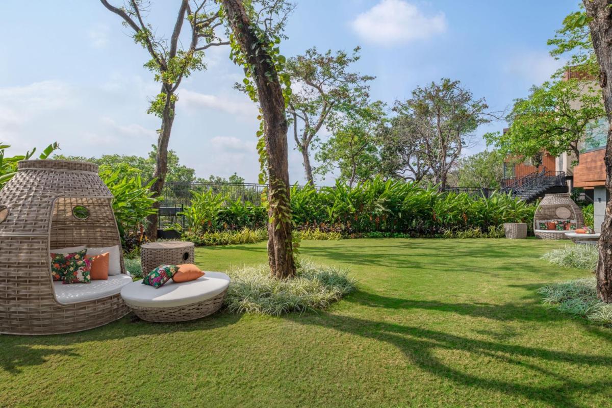 a garden with a bench and trees and grass at JW Marriott Goa in Vagator a garden with a bench and trees and grass at JW Marriott Goa in Vagator