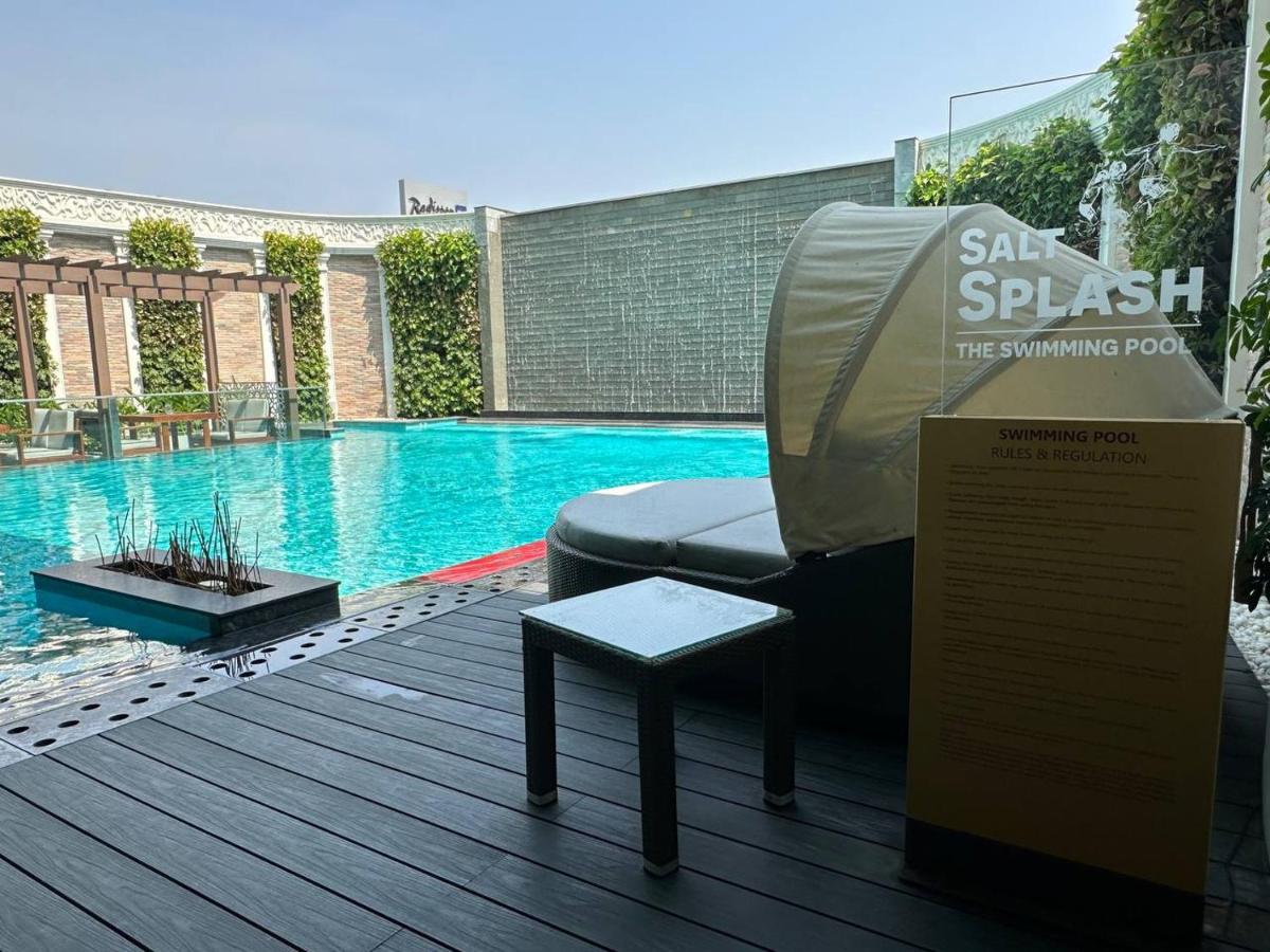 a swimming pool with a chair and a table on a deck at Radisson Blu Hotel & Suites GRT Chennai in Chennai