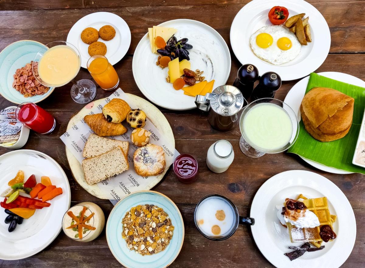 a wooden table with plates of breakfast foods and drinks at Renaissance Bengaluru Race Course Hotel in Bengaluru