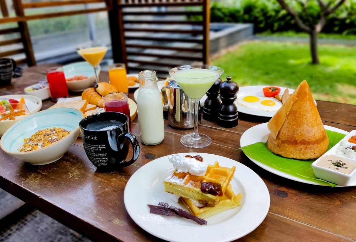 a wooden table topped with plates of food and drinks at Renaissance Bengaluru Race Course Hotel in Bengaluru