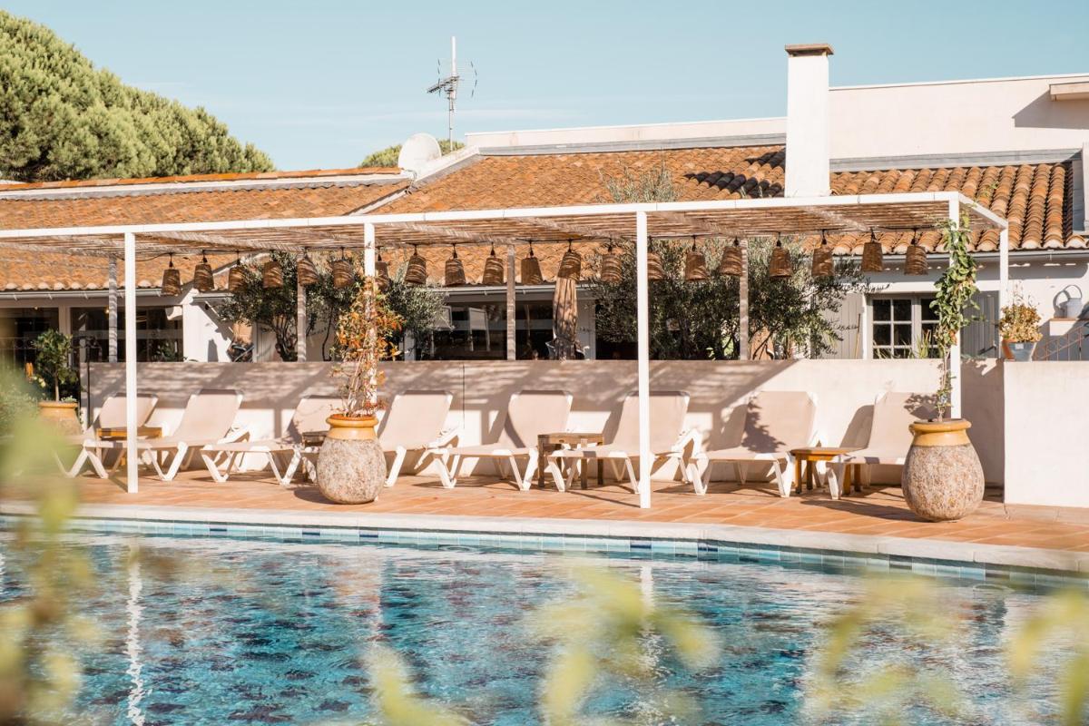 une terrasse avec des chaises et une piscine dans l'établissement Oustau Camarguen Hôtel & Spa, au Grau-du-Roi