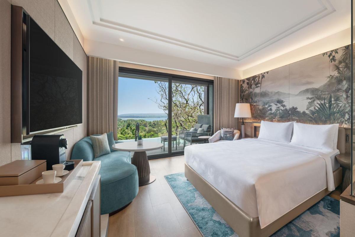 a hotel room with a bed and a large window at JW Marriott Goa in Vagator a hotel room with a bed and a large window at JW Marriott Goa in Vagator
