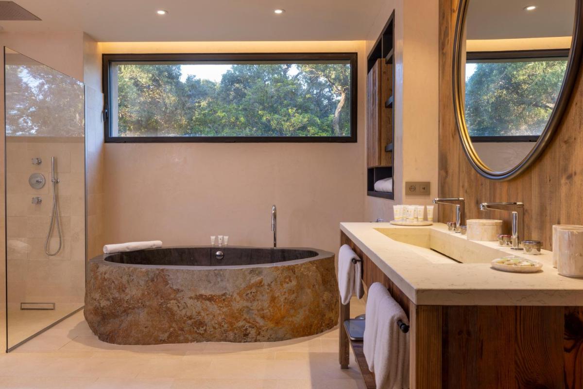 une salle de bains avec une grande baignoire au milieu dans l'établissement Les Regalia Hôtel & Spa, à Sainte-Lucie de Porto-Vecchio
